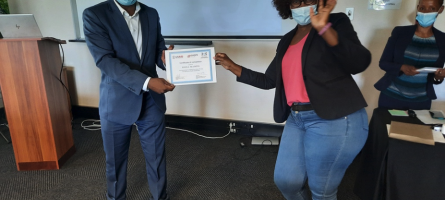 A man and a woman wearing masks and holding a certificate